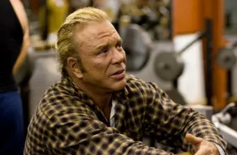 Mickey Rourke in checkered shirt sitting and looking sideways