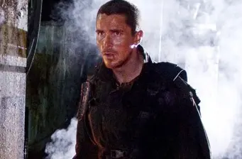 Man in tactical gear stands alerted with smoke in background