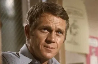 Close-up headshot of actor Steve McQueen indoors looking sideways