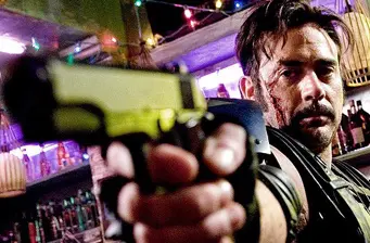 bloodied man aiming gun indoors with colorful lights behind