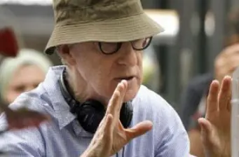 Woody Allen in hat and glasses gesturing with hands