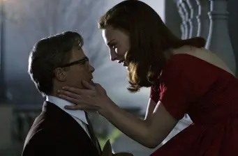 woman in red dress holds man's face close in tense movie scene