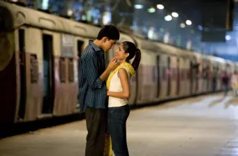 man and woman embrace near train on nighttime platform