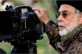 Francis Ford Coppola adjusting camera outdoors wearing beret and glasses