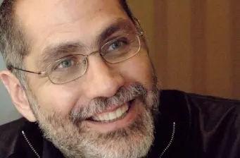 Smiling man with glasses and beard wearing black jacket