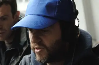man in blue cap and headset looks down indoors