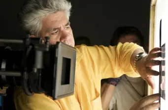 Man in yellow shirt adjusts film light on movie set