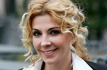Headshot of actress Natasha Richardson smiling outdoors with curly blond hair