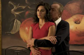 Man embracing woman from behind in front of large fruit painting