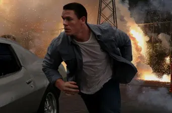 John Cena running from explosion beside a gray car