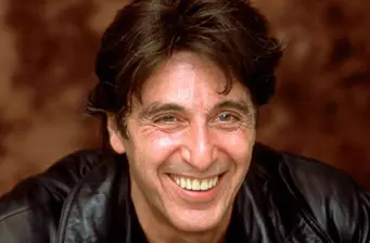 Al Pacino headshot smiling with brown background