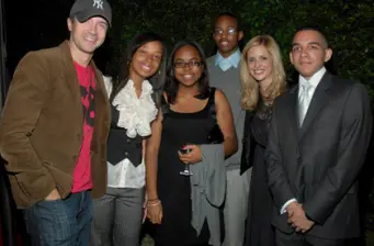 six people posing together outside, some in suits, one with drink