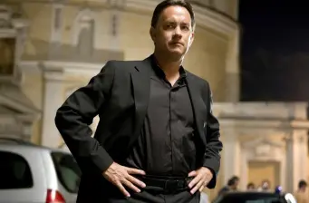 Man in black suit standing outdoors with historic building behind