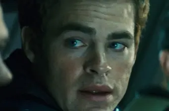Close-up of man with blue eyes looking sideways in dim lighting