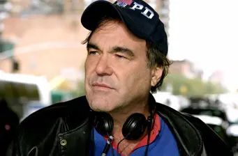 Oliver Stone wearing NYPD cap and headphones outdoors