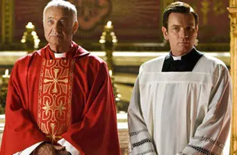 two priests in red and white robes inside church setting