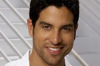 Headshot of Adam Rodriguez smiling against a blurred background