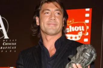 Javier Bardem holding award statue at an event, smiling