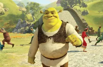 Shrek walking outdoors with villagers behind on sunny day