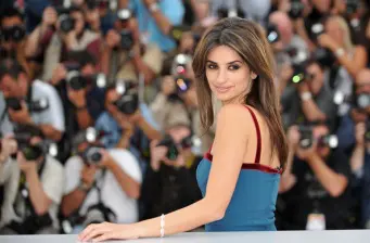 a woman in a blue dress posing with photographers in background