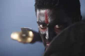 man with black and red face paint aiming gun intensely