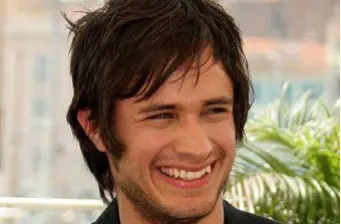 Headshot of Gael Garcia Bernal smiling outdoors with greenery background