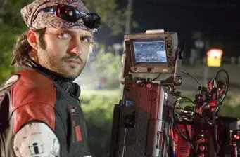 man with bandana and sunglasses on professional film camera at night