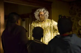 Woman in yellow gown talks to three people in dark room