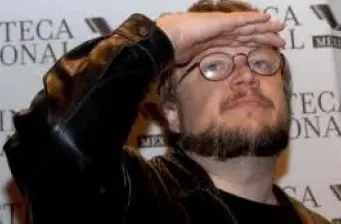 Guillermo del Toro shielding eyes with hand at press event