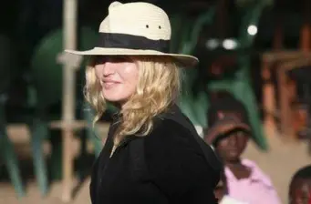 Madonna wearing white hat and black jacket outdoors directing
