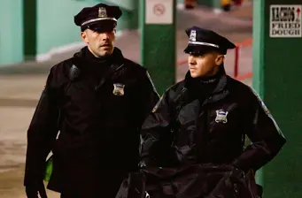 Two police officers in uniform walking outside at night