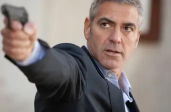 man in suit aiming handgun with serious expression