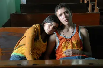 young woman leans on young man’s shoulder on wooden benches