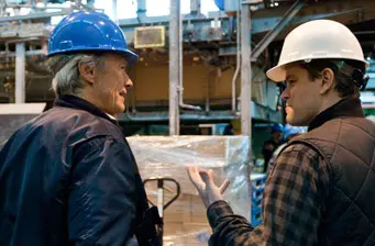 Clint Eastwood and Matt Damon in conversation on set with helmets