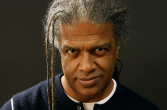 Headshot of man with gray dreadlocks and intense expression