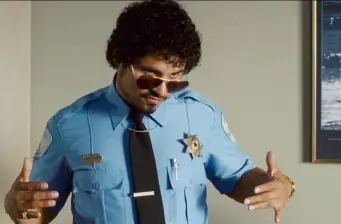 Man in blue police uniform wearing sunglasses gestures with hands