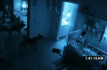 Child in crib with dog nearby in dim room, night vision effect