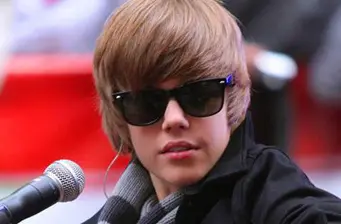 Justin Bieber wearing sunglasses speaking into microphone, casual look