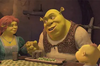 Shrek holding hands with family at dinner table in animated scene
