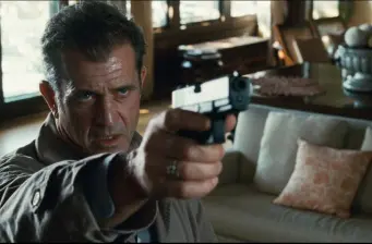 Man aiming handgun inside a living room with couch and cushions