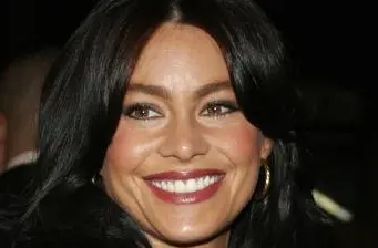 Smiling woman with dark hair and hoop earrings headshot