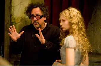 Man directs young woman in dress on movie set