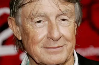 Headshot of director Joel Schumacher with red background