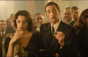 Penelope Cruz smokes as Adrien Brody speaks in formal setting