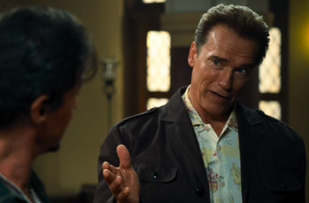 Man in jacket gestures while talking to another man in The Expendables