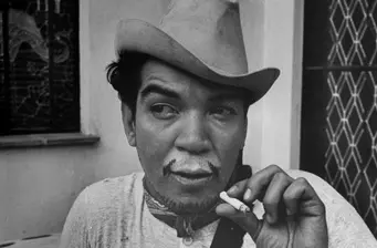 Man in cowboy hat holding cigarette and looking to the side