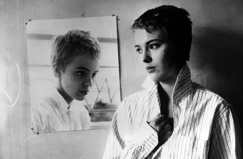 woman with short hair looks at reflection in mirror