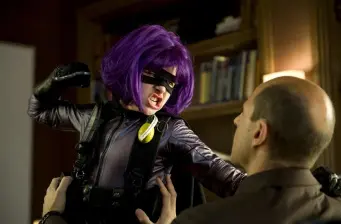 Hit-Girl in purple wig punches man in suit in fight scene