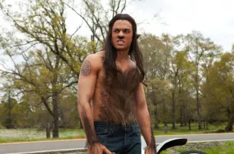 man outdoors with heavy body hair makeup near road, intense face