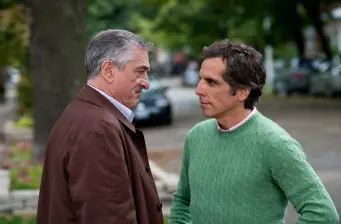 two men in conversation, one in brown jacket, the other in green sweater